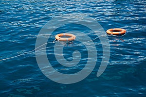 Orange life buoys floating on the surface of blue water