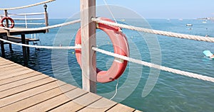 Orange life buoys on the mast against background of sea on sunny day