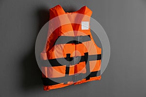 Orange life jacket on grey background. Personal flotation device photo