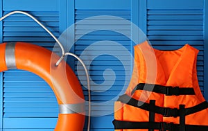 Orange life jacket and lifebuoy on blue wooden background. Rescue equipment