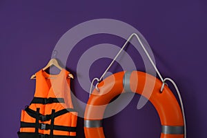 Orange life jacket and lifebuoy on violet background. Rescue equipment