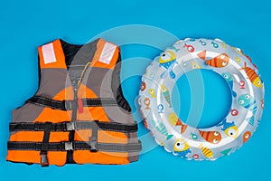 Orange life jacket and paddling inflatable circle for children, concept of summer and saving life on water