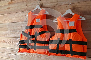 Orange life jackets on wooden background. Personal flotation device