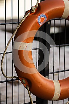 an orange life preserver is tied to a fence with a black metal post