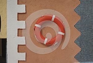 Orange life ring on terracotta wall