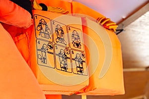 Orange life vests on a ship, closeup on the use instructions, detail How to put on, putting on a life jacket, shallow dof