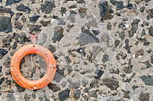 An orange lifebelt on a old stone wall