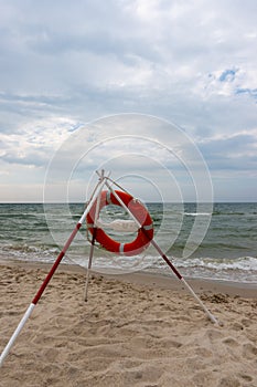 An orange lifeboat and reach extenders stuck in the sand on the beach.