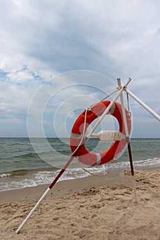 An orange lifeboat and reach extenders stuck in the sand on the beach.