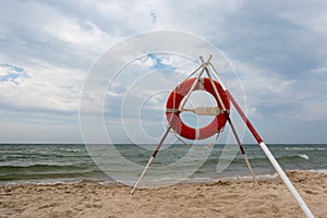 An orange lifeboat and reach extenders stuck in the sand on the beach.