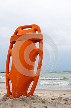 An orange lifeboat stuck in the sand on the beach.