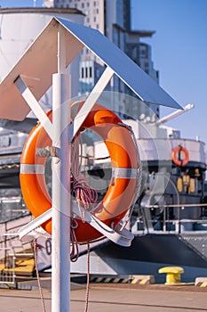 Orange lifebuoy on beach by sea. Safety equipment for rescuing people on seashore. Orange lifebuoy on the pier of blue