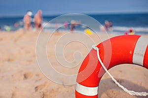 Orange lifebuoy in foreground. Blue clear sky, sea and people in