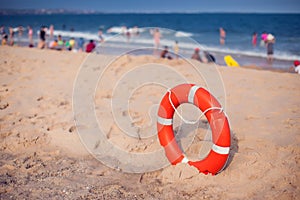 Orange lifebuoy in foreground. Blue clear sky, sea and people in