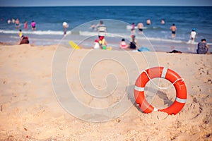 Orange lifebuoy in foreground. Blue clear sky, sea and people in