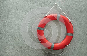 Orange lifebuoy with grey strips Rescue ring buoy .hanging on small gravel wall near swimming pool