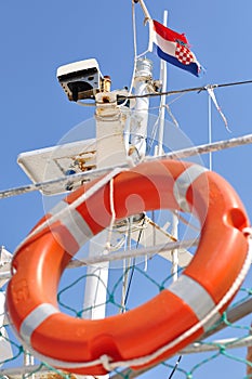 Orange lifebuoy hanging on ship with Croatian flag