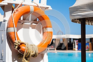 Orange lifebuoy hanging on white Lookout tower near public swimming pool Rescue and insurance concept