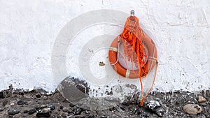 Orange lifebuoy hanging on white wall