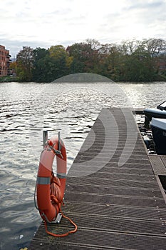 A orange lifebuoy hangs from a pole at the Spree River pier. Berlin, Germany