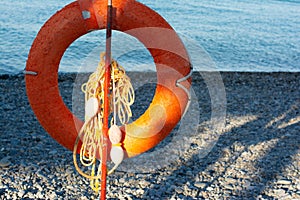 An orange lifebuoy lies on the seashore. The concept of rescue on the waters