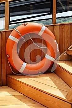 Orange lifebuoy and old rope hanging on a boat