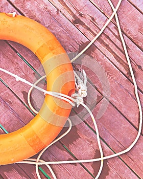 Orange lifebuoy with rope on a wooden pier near sea.