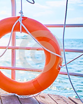 Orange lifebuoy with rope on a wooden pier near sea.