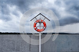 Orange lifebuoy on a stand on harbor pier