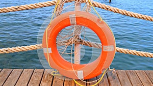 Orange lifeline and sea ropes on the background of the sea and blue sky. Marine ropes and life preserver hanging on a