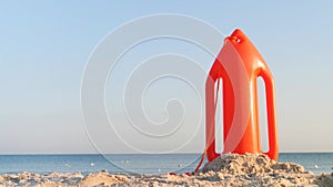 Orange lifesaver at the beach. Calm sea with waves and lifeguard rescue orange buoy on the sand. Safe vacation, travel insurance