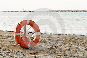 Orange lifesaver, life buoy or rescue buoy on sandy beach