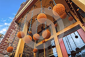 Orange light balls hanging at the entrance of a building with red brick wall