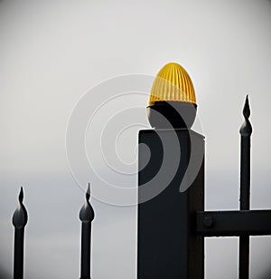 Orange light bulb on black metal fence