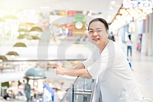 Orange Light effect in image of Asian long hair man who stands and smile in front of terrace in deparment store. it sparkles