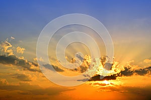 Orange light with sun rays and dark clouds on sky.