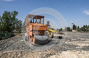 Orange light Vibration roller compactor standing on a stones at road construction and repairing asphalt pavement works