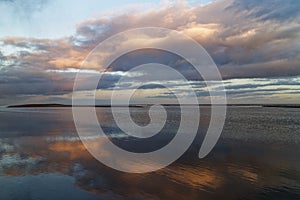 The orange light of a Winter Sunset reflecting in the calm shallow water around the sand banks of St Cyrus Beach