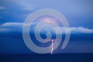 Orange lightning over the sea strikes through the cloud