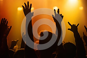 Orange lights, hands of people at concert or music festival dancing with energy in silhouette at live event. Dance, fun