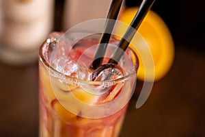 Orange long drink with grenadine and ice on wooden table