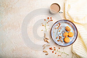 Orange macarons or macaroons cakes with cup of coffee on a white concrete background. Top view, copy space