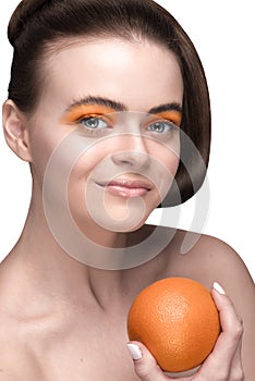 Orange make-up on a nice photo model holding an orange in her hand / offer