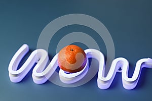 Orange mandarin instead of letter O in the neon sign of the word wow.