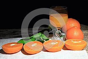 Orange mandarin or tangerine fruits, with green leaves and oranges juices in glass on wooden board background.