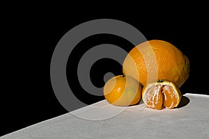 Orange and mandarins on white table with black background