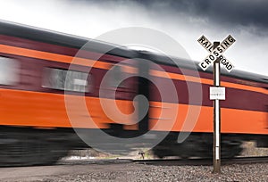 Orange & Maroon Passenger Car Flies by Railroad Crossing