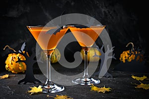 Orange martini cocktails with bats and decor for Halloween party, on dark