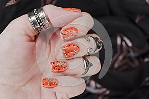 Orange matte nails on black blurry star background. Halloween nail art