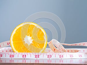 Orange with measuring tape on a wooden table.